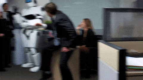 A group of people in an office laughing with a robot