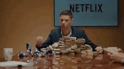 Mikey Day in front of a pile of money, handing it out saying, 'Here's money! Go!'