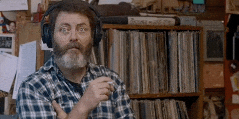 Nick Offerman pointing to his headphones and mouthing that he cant hear