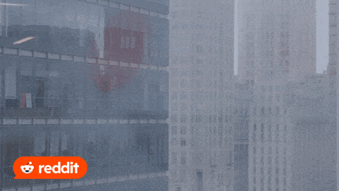 Snoo the Reddit mascot looking out the window of a high rise building and seeing his reflection in the glass