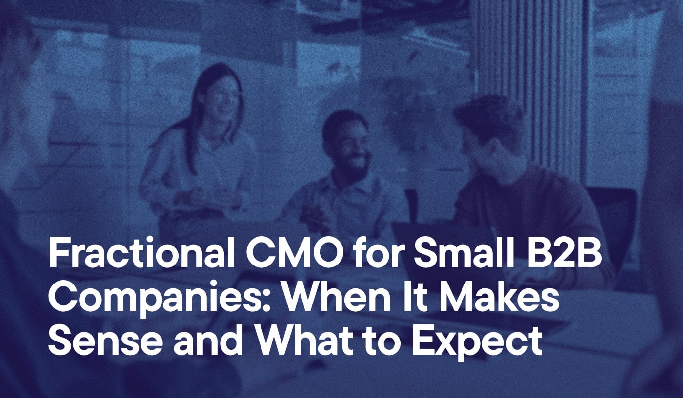 Fractional CMO for Small B2B Companies- When It Makes Sense and What to Expect overlayed on an image of coworkers in a conference room, working with their laptops. They are smiling.