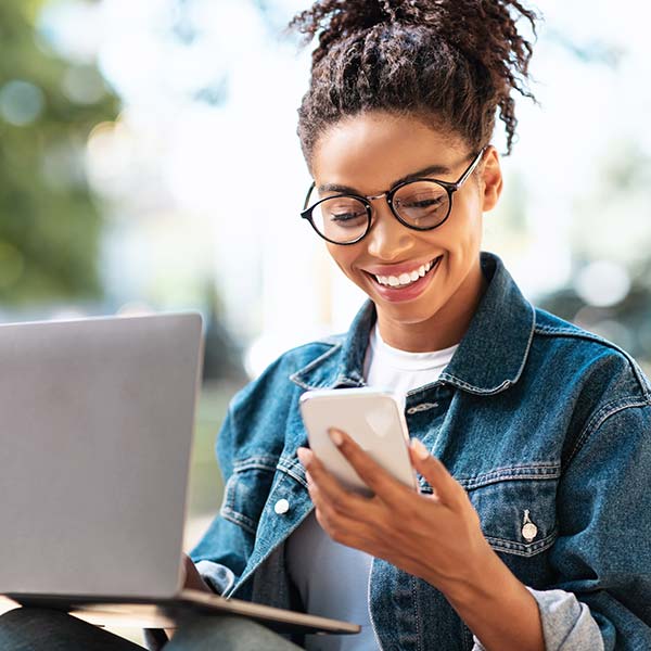 Woman working outside on phone and laptop