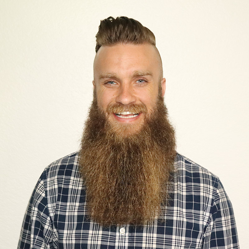 Photo of Jeffrey Howard, smiling in front of a taupe wall